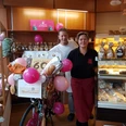 Café & Konditorei Nollmann Team Eine Bäckerei feiert 60 Jahre. Zwei Personen lächeln neben einem dekorierten Fahrrad voller Brot.