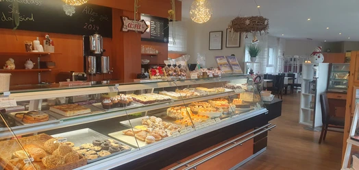 Café & Konditorei Nollmann Theke Ein gemütliches Café mit einer Vielfalt an Gebäck und Kuchen in einer einladenden Auslage.