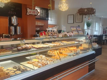 Café & Konditorei Nollmann Theke Ein gemütliches Café mit einer Vielfalt an Gebäck und Kuchen in einer einladenden Auslage.