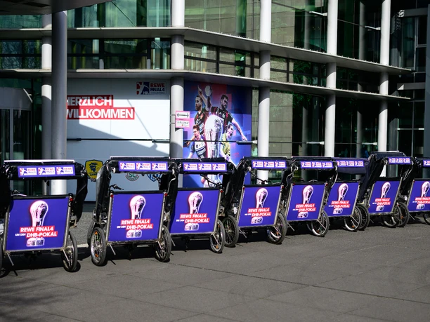 Rikolonia_Event Handball I.jpeg Series of advertising lights for the REWE final of the DFB Cup season in front of a modern hall.</p> <p