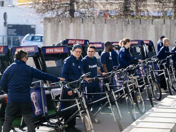 Rikolonia_Event VIP Shuttle.jpeg People in blue clothing lined up with bicycle rickshaws in an urban environment.</p> <p