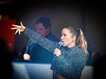 Frauenthal-Expo-Wien-PLUS-Messeband-Entertainment-DJplus-08.jpg Sängerin in glitzerndem Oberteil singt mit Mikrofon, hält Hand gestreckt in dynamischer Pose.</p>Singer in glittering top sings with microphone, holds hand outstretched in dynamic pose.</p> <p