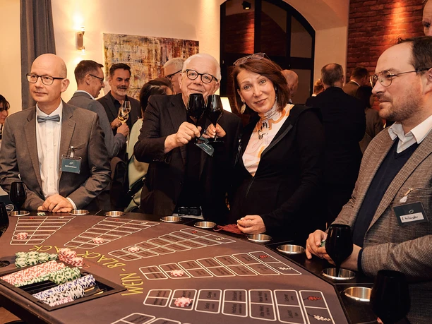 Casino Vinophil. Black-Jack Tisch Gruppe von Personen genießt geselliges Beisammensein an einem Spieltisch bei einem Event im Innenraum.</p>