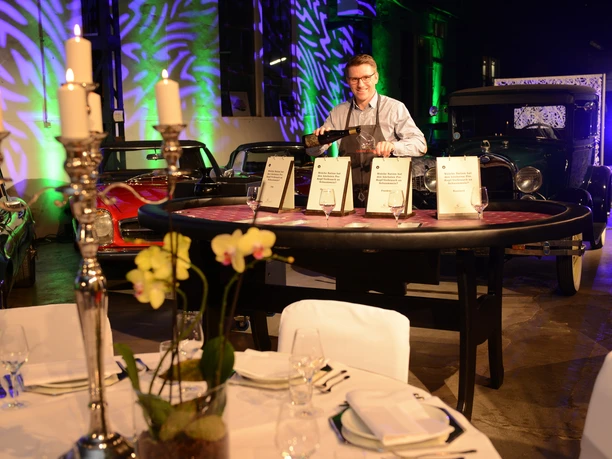 Casino Vinophil. Genuss-Quiz Tisch Classic cars surround a stylishly designed gala with candlesticks and laid tables.