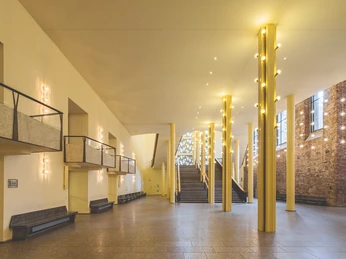 Gürzenich Köln, Erdgeschoss-Foyer Leerer, lichtdurchfluteter Saal mit Marmorelementen, Treppenaufgang und modernen Leuchten.Empty, light-flooded hall with marble elements, staircase and modern lighting.