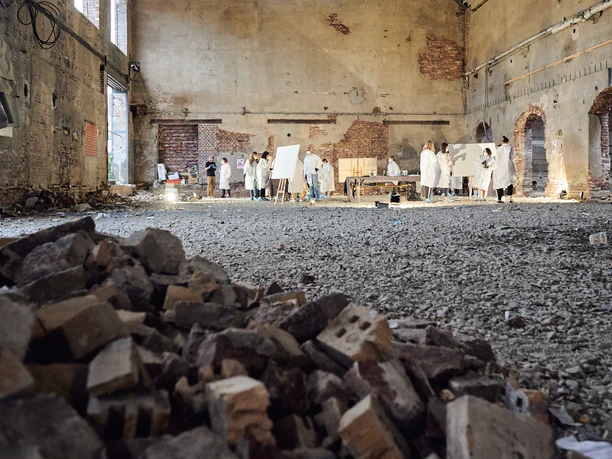 Cologne Graffiti. Urbane Location Künstler in weißer Kleidung malen in einer großen, verlassenen Industriehalle mit Ziegelhaufen.</p>