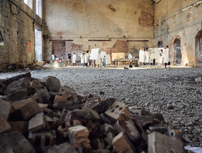 Cologne Graffiti. Urbane Location Künstler in weißer Kleidung malen in einer großen, verlassenen Industriehalle mit Ziegelhaufen.</p>Artists in white clothing paint in a large, abandoned industrial hall with piles of bricks.</p> <p