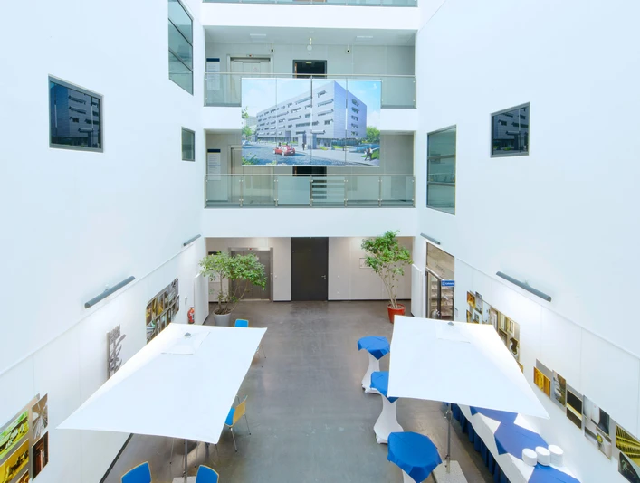 ZMMK-Foyer Modernes, lichtdurchflutetes Atrium mit Glaskuppel und mehreren Etagen, dekoriert mit Tischen.Modern, light-flooded atrium with glass dome and several floors, decorated with tables.