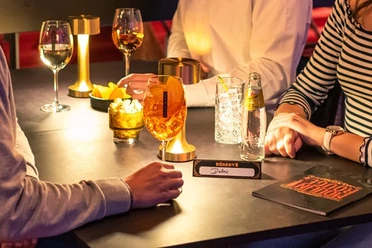 MDK_Gruppe_1 Eine gemütliche Bar, Menschen bei Getränken, gedimmtes Licht, atmosphärisch und gesellig.