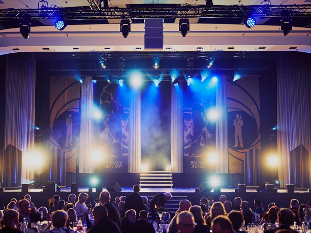 Chariot_Maritim_005 Bühne mit blauem Licht, Showtreppe, rundes Publikum; Gala-Event-Stimmung in elegantem Saal.