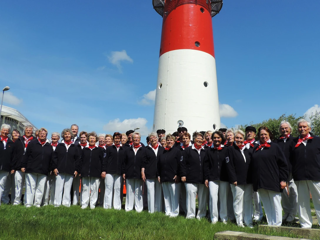 Chor2014_2560x1707.jpg Eine Gruppe Menschen in weißen Hosen und blauen Oberteilen. Im Hintergrund ein Leuchtturm.