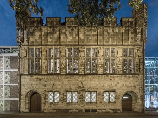 Gürzenich Köln, Außenansicht Historic half-timbered house in modern surroundings at night, illuminated, with large windows.</p> <p