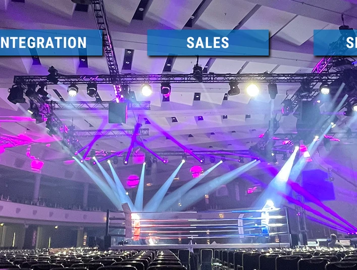 KKT_HEADER_2024.jpg Eine spektakulär beleuchtete Eventhalle mit leeren Sitzreihen und einem Boxring im Zentrum.A spectacularly illuminated event hall with empty rows of seats and a boxing ring in the center.