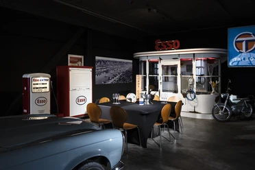 04_CC_PrivateDinner.jpg Retro-Essenzapfsäule und Esso-Diner mit Oldtimer-Motorrad in einem nostalgischen Ausstellungsraum.