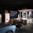 04_CC_PrivateDinner.jpg Retro-Essenzapfsäule und Esso-Diner mit Oldtimer-Motorrad in einem nostalgischen Ausstellungsraum.Retro petrol pump and Esso diner with vintage motorcycle in a nostalgic showroom.