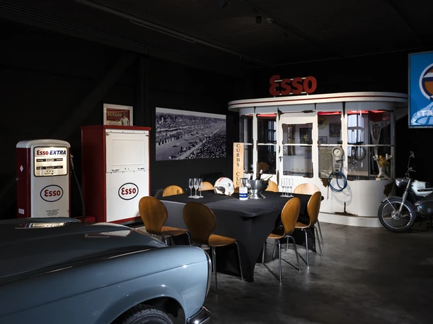 04_CC_PrivateDinner.jpg Retro-Essenzapfsäule und Esso-Diner mit Oldtimer-Motorrad in einem nostalgischen Ausstellungsraum.