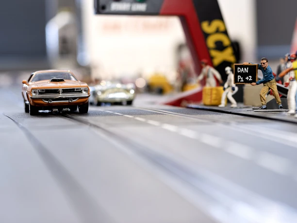 _MG_0557.jpg Rennauto auf Miniaturstrecke mit Figuren am Rand in einer Modelllandschaft.