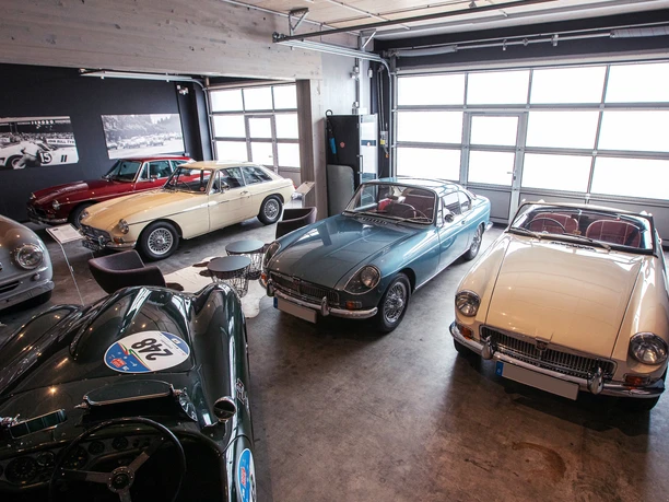 IMG_7078.jpg Alte Sportwagen in einer stilvollen Halle mit Betonwänden und großen Fenstern.