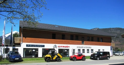 Auto Burgdorf Farchant Haus mit Büro und Ausstellungsraum, davor stehen 3 Autos und ein kleiner Bagger