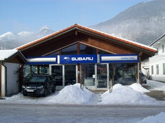 Auto Heigl Farchant Frontansicht eines Hauses mit dem Schild Subaru, Günther Heigl. Davor steht ein Auto, daneben befinden sich ein paar Schneehaufen