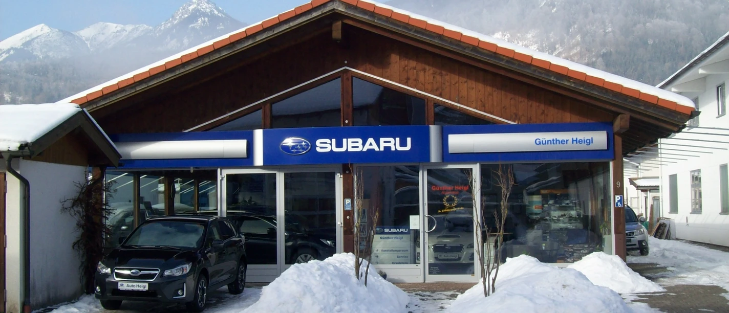 Auto Heigl Farchant Frontansicht eines Hauses mit dem Schild Subaru, Günther Heigl. Davor steht ein Auto, daneben befinden sich ein paar Schneehaufen