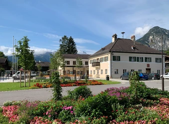 Rathaus-Fundbüro Farchant Rathaus Farchant, davor Blumenbeet im Hintergrund Bäume, der Kramer und weiter hinten das Wettersteingebirge mit Zugspitze