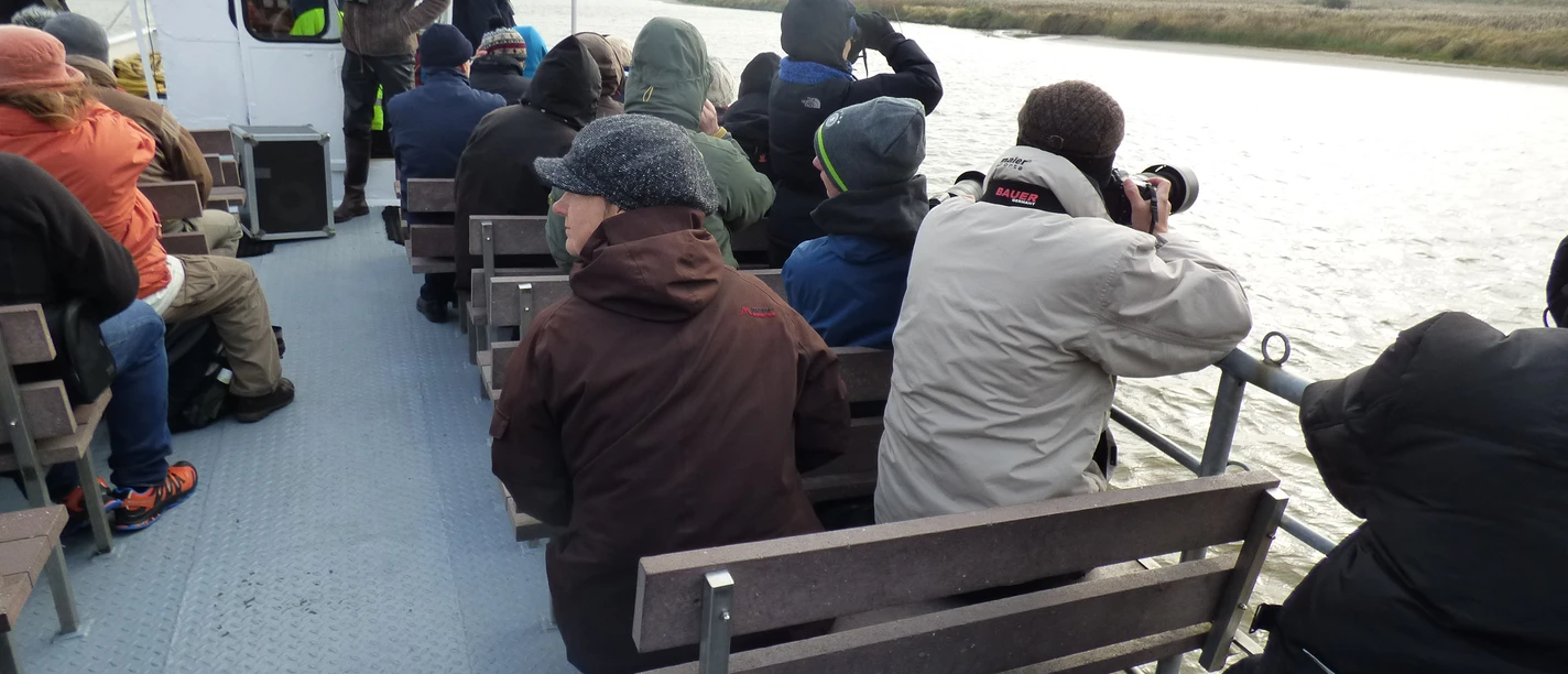 Oben an Deck Fahrgäste auf dem Außendeck eines Ausflugsschiffs beobachten Ufer und Wasser.