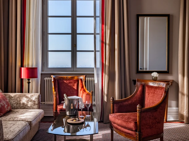 Dom Suite A stylishly furnished living room with red armchairs, sofa and a window that lets in natural light.