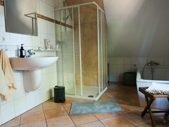 2023-06-HausGörlich-19.jpg Modernes Badezimmer mit Fliesenboden, Glasduschkabine, Waschbecken und Badewanne, hell beleuchtet.