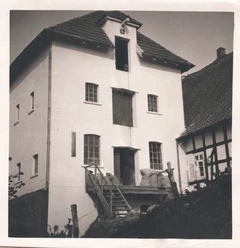 tengern-finkmanns-muehle-01.jpg Historische dreistöckige Mühle mit Dachgauben und antiken Fenstern, flankiert von Fachwerkgebäuden.