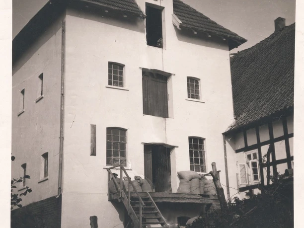 tengern-finkmanns-muehle-01.jpg Historische dreistöckige Mühle mit Dachgauben und antiken Fenstern, flankiert von Fachwerkgebäuden.