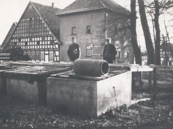 tengern-finkmanns-muehle-03.jpg Historische Ansicht der Finkmanns Mühle in Tengern mit Fachwerkgebäude und zwei Männern im Vordergrund.
