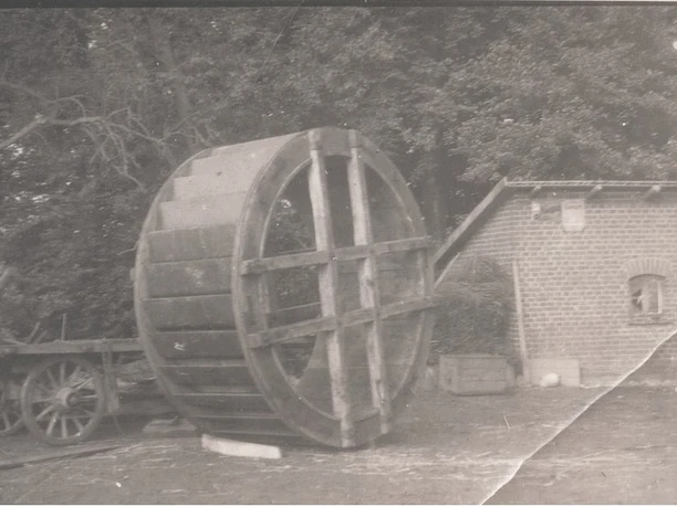 tengern-finkmanns-muehle-04.jpg Altes Schwarzweißfoto einer historischen Wassermühle mit einem großen hölzernen Mühlrad im Freien.