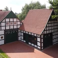 tengern-kutscherhaus-backhaus.jpg Fachwerkgebäude mit roten Ziegeldächern in bewaldeter Umgebung, umgeben von einer zum Teil gepflasterten Fläche.