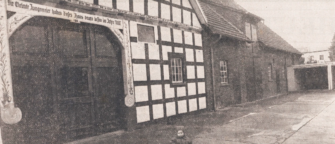 tengern-hof-jungemeier.jpg Historisches Fachwerkgebäude mit Torbogen, datiert 1815, altmodisch schwarz-weiß, kleines Kind vorne.