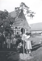 tengern-kahre-hof.jpg Eine Gruppe von Menschen pflanzt feierlich einen Baum vor einem historischen Fachwerkgebäude.