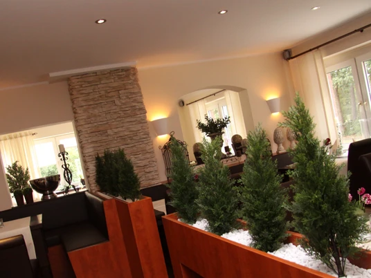 Restaurant im Landhaus Jägerkrug Helles Restaurant mit moderner Einrichtung, Steinwand, Pflanzen und großen Fenstern für Tageslicht.