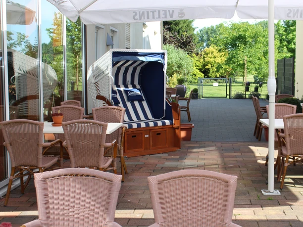 Landhaus Jägerkrug - Terrasse Sonnige Terrasse mit Strandkörben, einladenden Sitzmöbeln und grünem Gartenblick im Landhaus Jägerkrug.