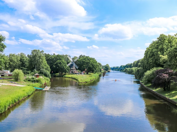 Höltingmühle in Meppen Historische Windmühle an einem ruhigen Flussufer mit Booten und grüner Uferlandschaft bei Meppen.