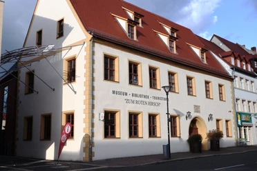 La maison de l'office du tourisme comprend également la bibliothèque municipale et le musée municipal. La façade est peinte de couleur claire et les fenêtres s'accordent avec le toit en tuiles traditionnel.