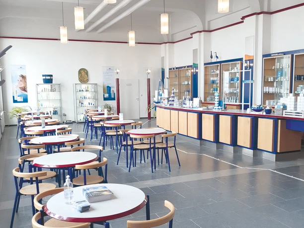 Innenansicht des BIOMARIS Shops in der Kurhalle Borkum mit Tischen, Stühlen und Produkten.Interior view of the BIOMARIS shop in the Borkum spa hall with tables, chairs, and products.