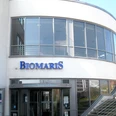 2024-02_BIOMARIS_Shop_Borkum_Gezeitenland.jpg Das BIOMARIS Shop-Gebäude auf Borkum liegt im Gezeitenland, mit modernem Glas- und Stahl-Design, dominiert von einem großen BIOMARIS-Logo.