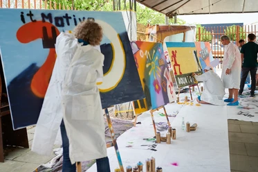 Cologne Graffiti. Teamarbeit Menschen malen farbenfrohe Graffitis auf großen Leinwänden in einem kreativen Außenbereich.</p>