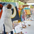 Cologne Graffiti. Teamarbeit People paint colorful graffiti on large canvases in a creative outdoor area.</p> <p