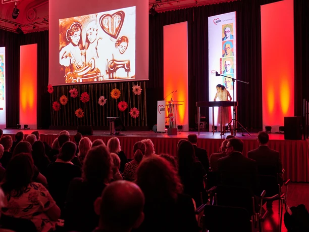 AWO 100-jähriges Jubiläum.jpg Concert hall with red light, musician at the keyboard, large projection of artworks on the wall.</p> <p