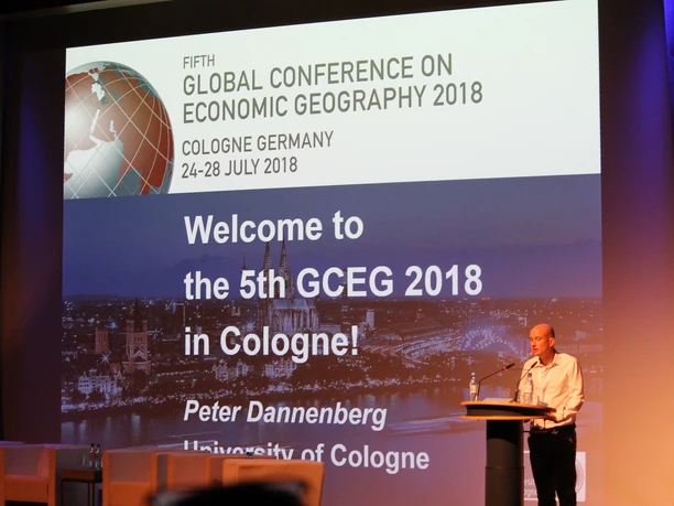 Global Conference on Economic Geography Welcome-Banner und Redner auf der World Conference, wirtschaftsgeografisches Event in Köln 2018.