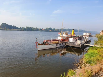 KaiserWilhelm©Dorothee Meyer (11).jpg Historic paddle steamer moored at a riverside pier on a calm, wide river under clear sky