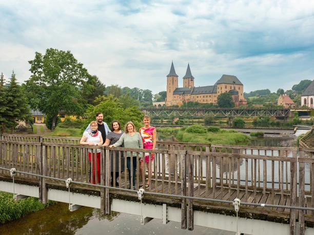 Týmová fotografie Turistické informace "Rochlitzer Muldental" Na snímku je tým turistických informací na mostě pro pěší přes řeku Mulde před zámkem Rochlitz.