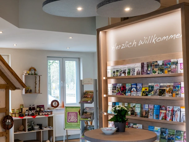 Bispingen-Touristik_.jpg Ein heller Raum mit Infobroschürenregal, einladend dekoriert, kleiner Tisch mit Blumen, Willkommenstext an der Wand.