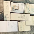 Urban Sketchers Mehrere geöffnete Skizzenbücher auf dem Boden zeigen unterschiedlich detaillierte urbane Zeichnungen von Straßenszenen mit Menschen und Architektur.